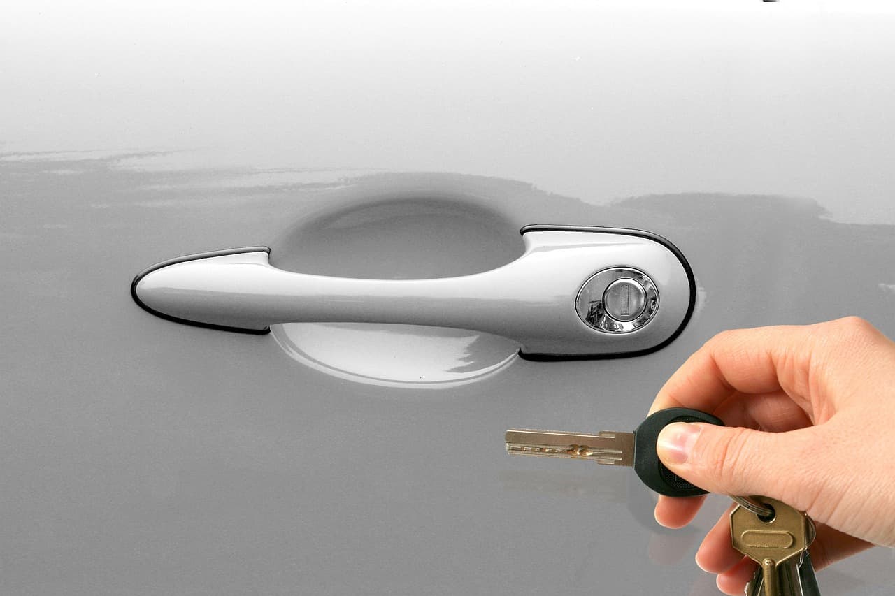 Car keys in a hand, next to the door handle